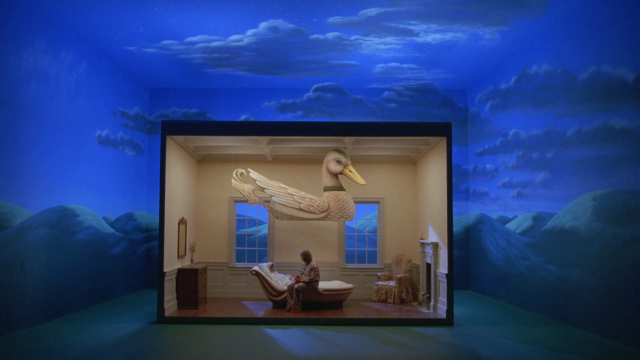 The Magritte inspiration is clear in shots like this. Compare to the below Magritte painting.