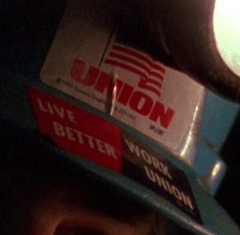 Close-up of last image. 2 stickers: cartoon American flag waving with 'UNION' in the same red as the red stripes of the flag. #2: 'LIVE BETTER | WORK UNION'. The left is in red and the right is in blue, both with white text.